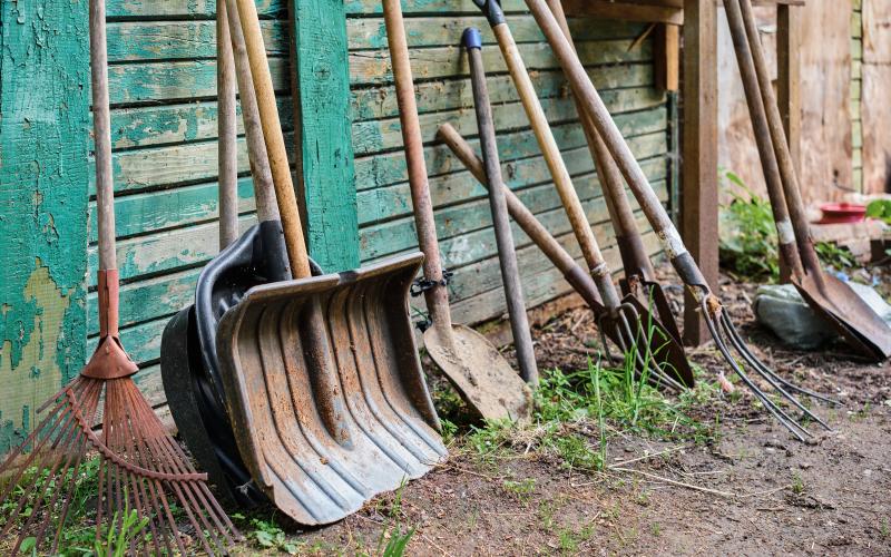 gardening-old-tools-on-a-wooden-peeled-green-wall-vegetable-garden-and-farming-equipment-selective-focus-hand-agricultural-tool-work-on-the-ground